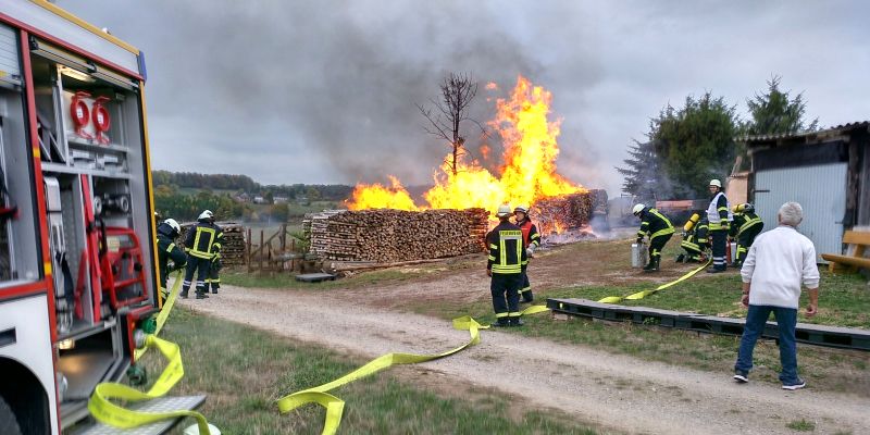 Holzstapel und Wiese stehen in Flammen